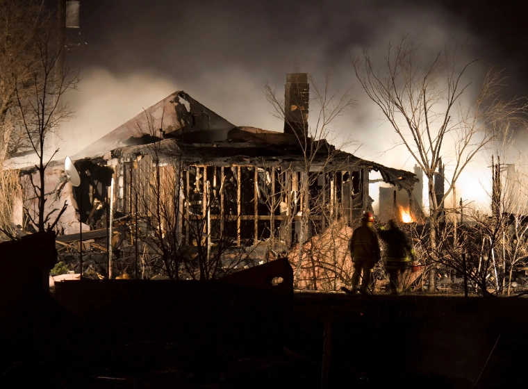 firemen at the aftermath of a house that got burnt down